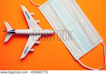 Savety Travel During Covid-19 Pandemic. Plane With Medical Face Mask On Yellow Background. Coronavir