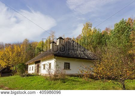 Old Ukrainian Wooden Farmhouse With Thatched Roof Built In The 19th Century, Autumn Day. Pyrohiv, Ky