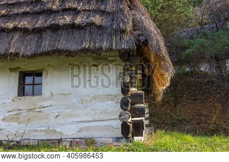Part Of A Whitwashed Log Wall With Small Window And Thatched Roof Of An Ancient Ukrainian Rural Hous