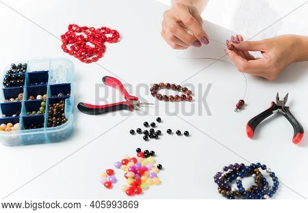 Jewelry Making. Making A Bracelet Of Colorful Beads. Female Hands With A Tool On A White Background.
