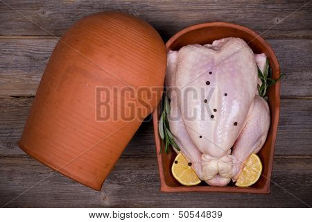 Preparing a chicken for roasting in a traditional terracotta chicken brick
