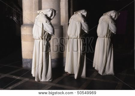 Hooded monks walking in a dark medieval church