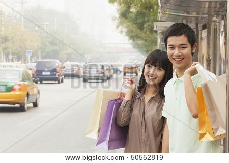 Portrait of smiling young couple at the bus stop, Beijing, China
