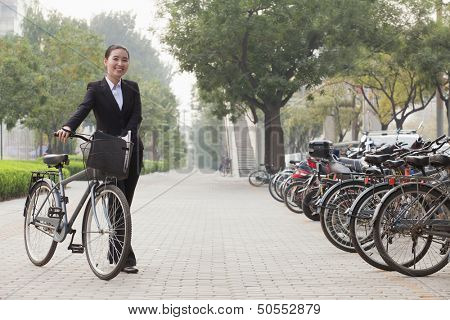 Young businesswoman holding a bicycle, sidewalk, Beijing
