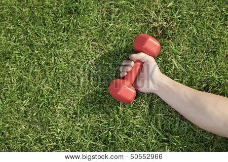 Close Up on Hand Holding Red Dumbbell in Grass