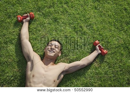 Shirtless Man Lying in Grass with Dumbbells in Beijing