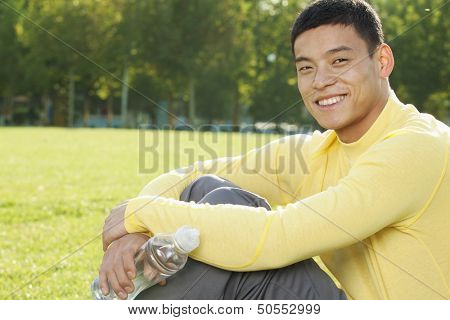 Young Athletic Man Sitting on the Grass in a Park