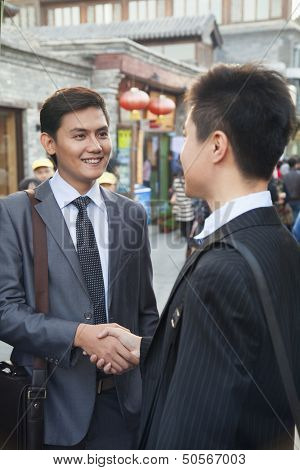 Two young businessman handshaking in houhai, Beijing, China