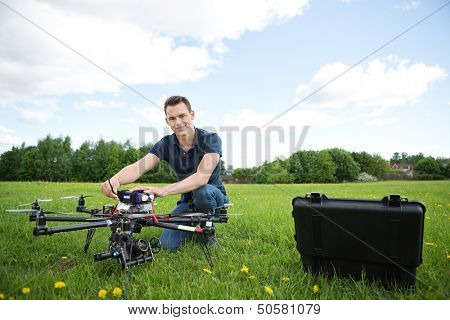Portrait of young technician assembling octocopter drone crouching in park