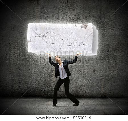 Image of young businesswoman holding burden above head