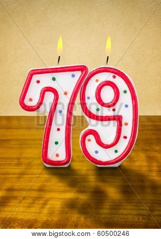 Burning birthday candles number 79 on a wooden background