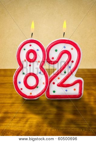 Burning birthday candles number 82 on a wooden background