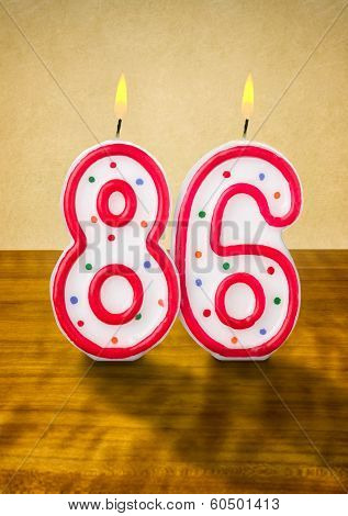 Burning birthday candles number 86 on a wooden background