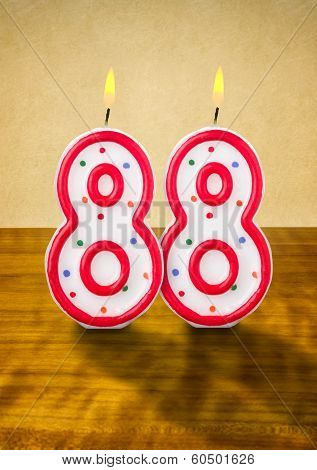 Burning birthday candles number 88 on a wooden background