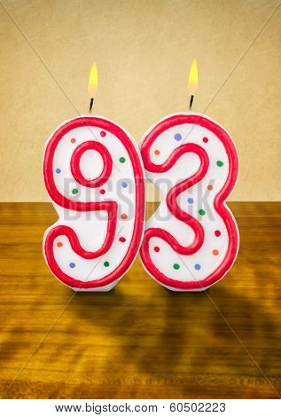 Burning birthday candles number 93 on a wooden background