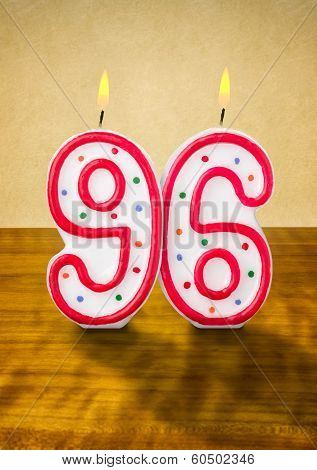 Burning birthday candles number 96 on a wooden background