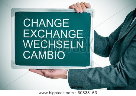 man wearing a suit holding a chalkboard with the words change, exchange, wechseln, cambio written in it