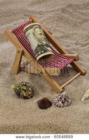 deck chair with dollars on the sandy beach. symbolic photo for travel costs, holidays, vacations. save on holiday