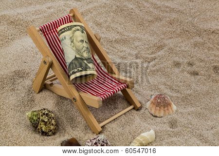 deck chair with dollars on the sandy beach. symbolic photo for travel costs, holidays, vacations. save on holiday
