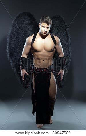 Handsome muscular guy posing as fallen angel