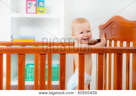 Baby boy standing in crib at home
