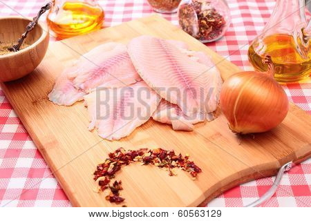 Raw fish tilapia on cutting board and spices