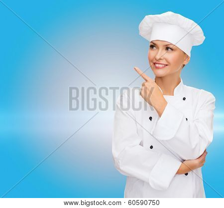 cooking, advertisement and food concept - smiling female chef, cook or baker pointing finger to something