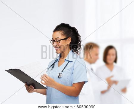 healthcare and medicine concept - smiling female african american doctor or nurse in eyeglasses with stethoscope and clipboard