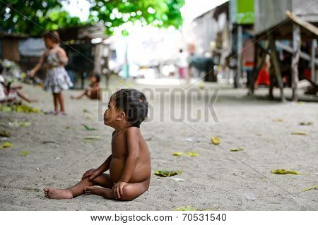naked poor kid sitting in the middle of the road