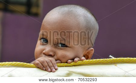 one poor little child looking at camera behind broken mattress