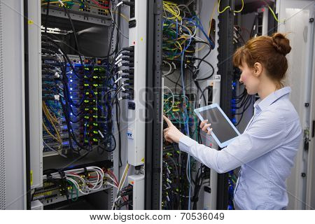 Technician using tablet pc while analysing server in large data center
