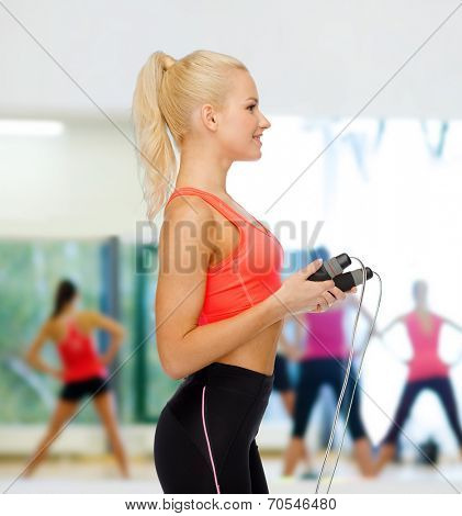 sport, exercise and healthcare concept - smiling sporty woman with skipping rope