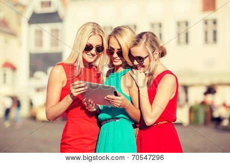 holidays and tourism concept - beautiful blonde girls toursits looking into tablet pc in the city