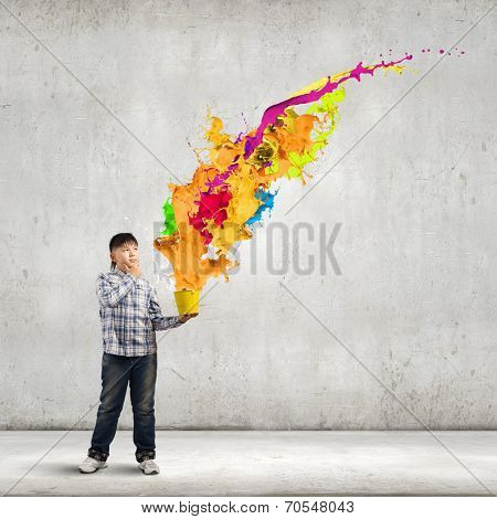 Young boy splashing colorful paint from bucket