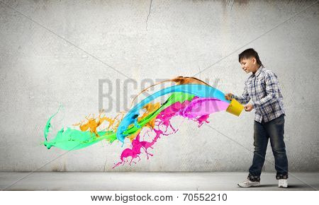 Young boy splashing colorful paint from bucket