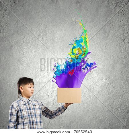 Young boy splashing colorful paint from carton box