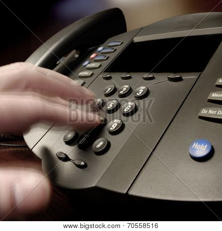 Hand diling on a phone in a business office