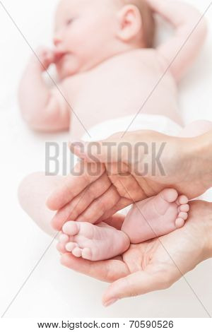 Mother Gently Hold Baby Girl Legs In Hands