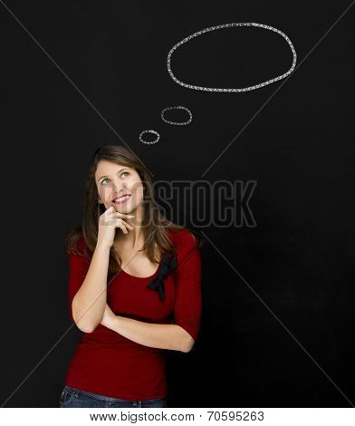 Beautiful young student having an idea, with a thougt ballon designed on a chalkboard