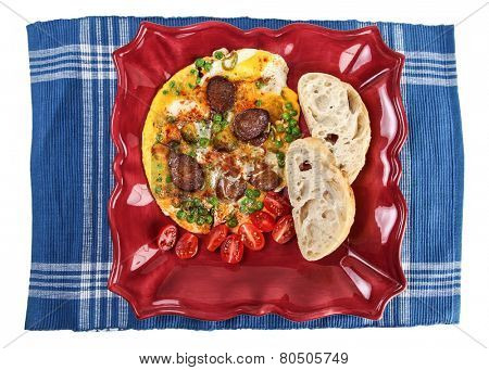 Omelet with sausage on plate and blue table mat isolated on white background