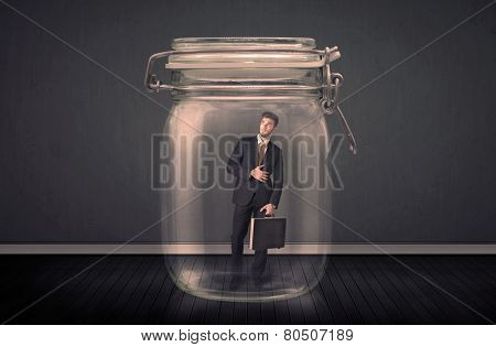Businessman trapped into a glass jar concept on background