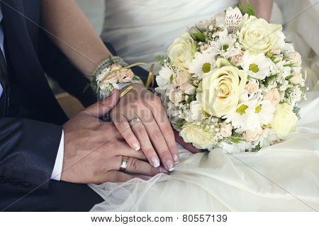 Bride And Groom's Hands With Wedding Rings And Bouquet Of Flowers