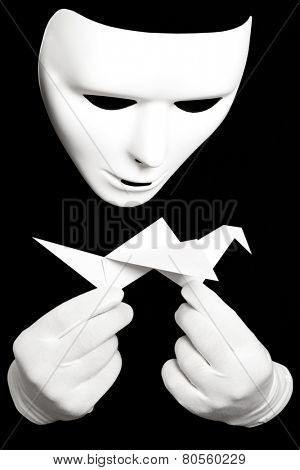 White theatrical mask and paper japanese crane isolated on black