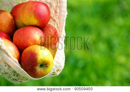 Red apple in hemline of female clothing, closeup