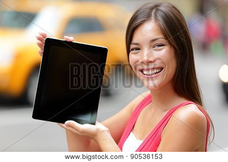 Tablet computer casual woman showing blank empty screen of tablet pc in New York City, standing in street with yellow taxi cab. Beautiful young mixed race female model in Manhattan, New York City.