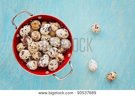 Quail Eggs In Red Collander On A Blue Wooden Background, Top View
