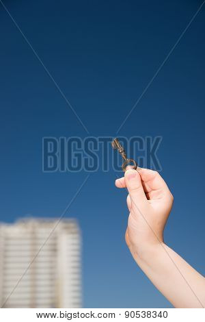 Child Hand Holding An Old Key To The House Against The Sky