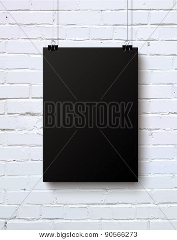 Black blank vertical piece of paper on the white brick wall