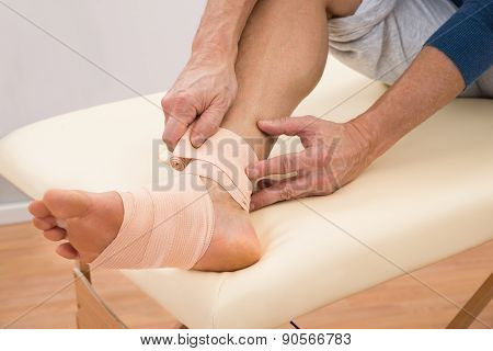 Man Putting Elastic Bandage On Foot