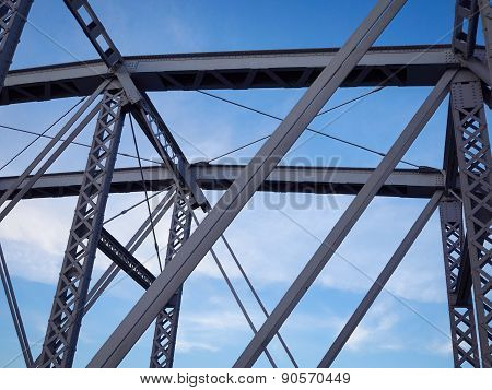 Detail of painted riveted bridge against blue sky.